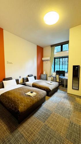 a hotel room with two beds and a living room at Yufuin Tabinokura in Yufuin