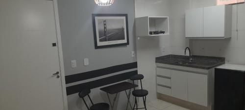 una cucina con armadi bianchi, lavandino e sgabelli di Apart 2 Qdras da Praia a Rio de Janeiro