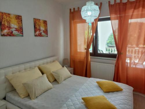 a bedroom with a bed with yellow pillows and a window at Vacation Home Keskic in Velika Gata