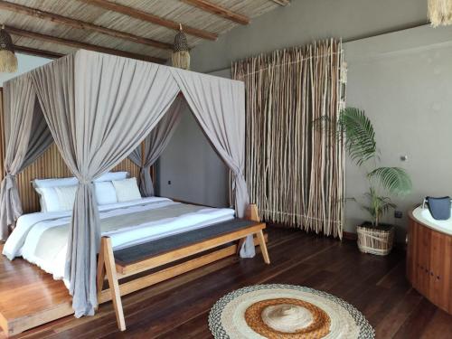 a bedroom with a bed with a mosquito net at La Spiaggia, tropical villa with private beach in Sainte Marie