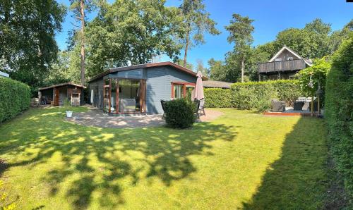 a small shed in a yard with a grass field at Dubbele chalet op recreatiepark Topparken op de Veluwe in Beekbergen met grote vrije tuin en eigen parkeerplaats in Beekbergen