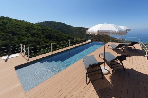 a swimming pool with chairs and an umbrella on a deck at Villa Ruya Cefalù in Cefalù