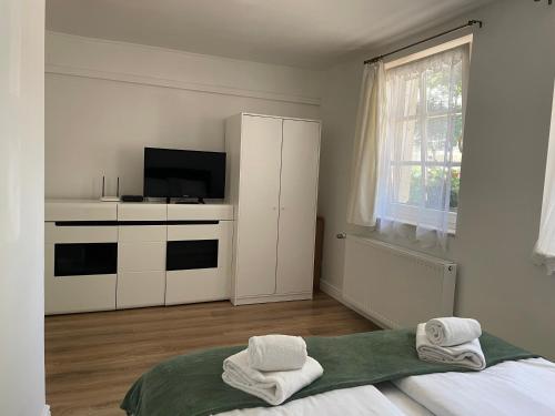 a white room with a bed and a tv at Gyopárosi Napsugár Vendégház in Orosháza