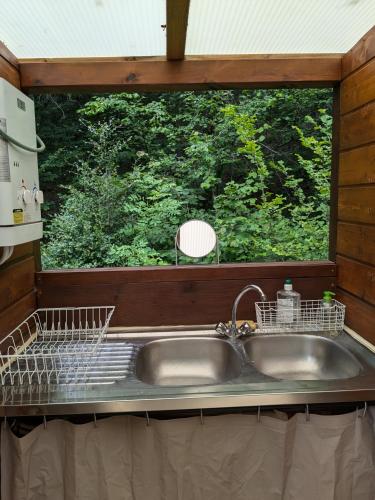 une cuisine avec un évier et une fenêtre dans l'établissement Lodge Bois et Toile avec Vue, à Doussard
