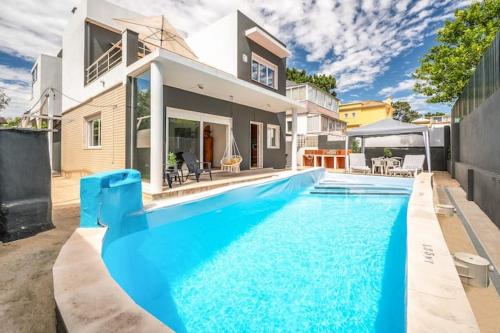 a large blue swimming pool in front of a house at Casa Férias Charneca da Caparica in Charneca
