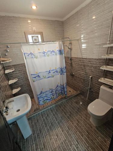 Un baño con cortina de ducha y lavabo. en Khiran City, en An Nāmī