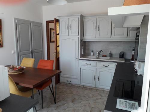une cuisine avec des armoires blanches et une table en bois dans l'établissement Jolie longère près de Beauval et Valençay, à Chabris