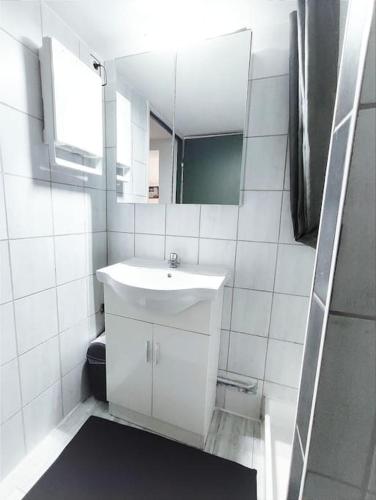 une salle de bain blanche avec un lavabo et un miroir dans l'établissement Émeraude proche hippodrome, à Aix-les-Bains