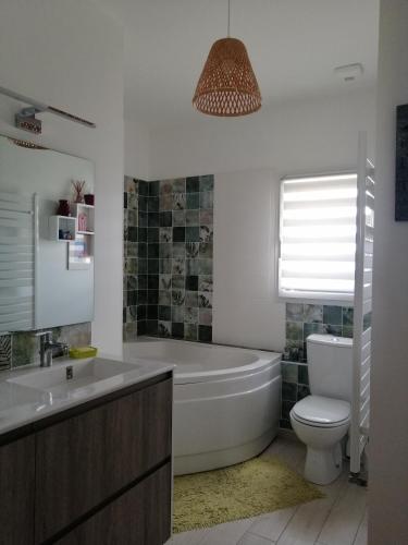 une salle de bain avec une baignoire, des toilettes et un lavabo dans l'établissement Maison de ville avec jardin en lisière de campagne, à Guérande