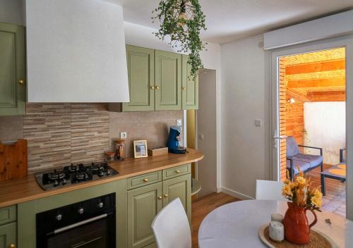 une cuisine avec des placards verts et une table dans l'établissement Solen évasion - L'aventurine - maison en Vendée, à La Roche-sur-Yon