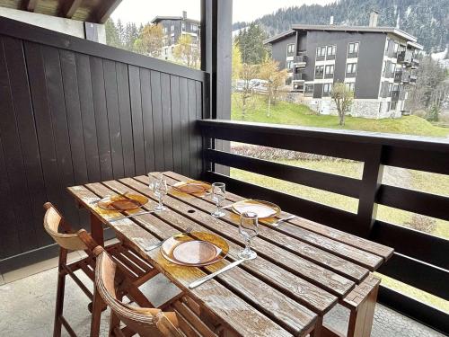 - une table en bois sur un balcon avec vue sur un bâtiment dans l'établissement Appartement 2 pièces+alcôve, 4 couchages, parking, Megève - FR-1-597-27, à Megève