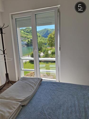 a bedroom with a bed and a large window at Apartments Sokolović in Višegrad