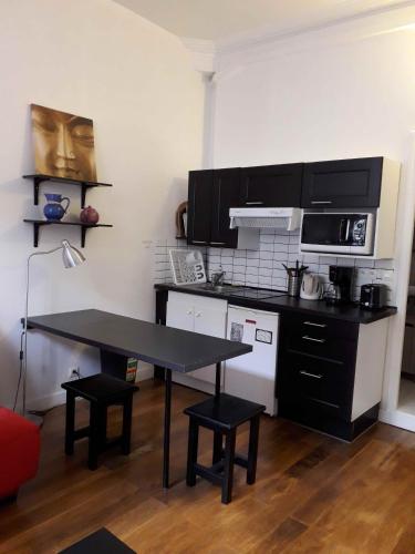 une petite cuisine avec une table et un micro-ondes dans l'établissement Studio de charme 20m2 à Saint-Mandé, à Saint-Mandé