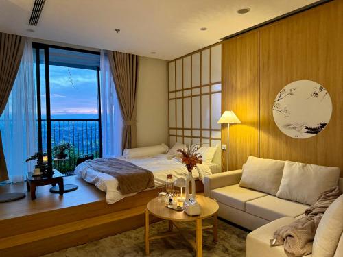 a bedroom with a bed and a couch and a window at Onsen Landmark Ecopark in Cong Luận