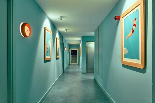 a hallway with blue walls and paintings on the walls at The Boc Hostels - Beach in Can Pastilla