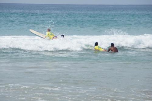 a group of people riding a wave on surfboards in the ocean at Ritas Hotel in Hikkaduwa