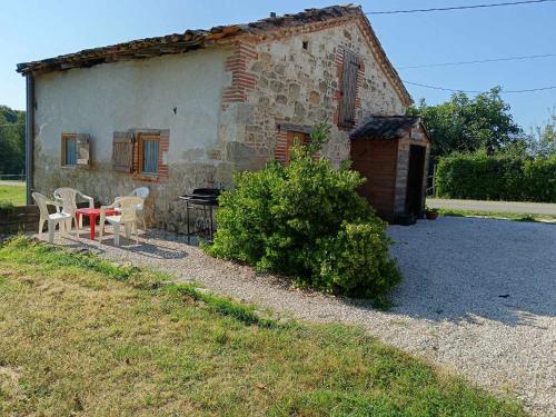a stone house with a table and chairs in front of it at Gîte FABEL HAUT in Durfort