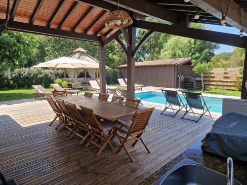 - une terrasse en bois avec une table et des chaises à côté de la piscine dans l'établissement Villa 12 personnes Avec piscine et vélos Proche océan, à Moliets-et-Maa