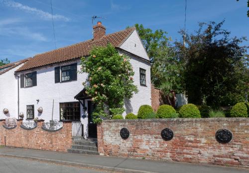 a white house with a brick wall at Rosehip Cottage Period home, Bingham, Nottingham in Bingham