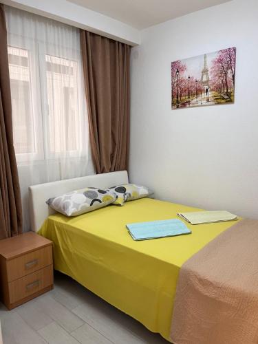 a bedroom with a yellow bed and a window at ID apartments in Tivat
