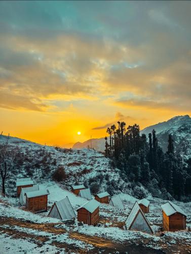 a snow covered village with the sunset in the background at Driftters in Chakrāta