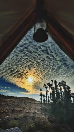 a view from the inside of a tent with a cloudy sky at Driftters in Chakrāta