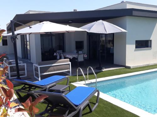 a patio with chairs and umbrellas next to a pool at Casa Ambiente Verde in Caldas da Rainha