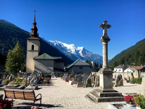 a church with a cross on a pole in a cemetery at Marmotte Mountain Manor in Chamonix-Mont-Blanc