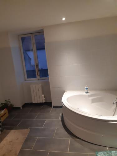 a white bath tub in a bathroom with a window at Chic et relax familial in Montmarault