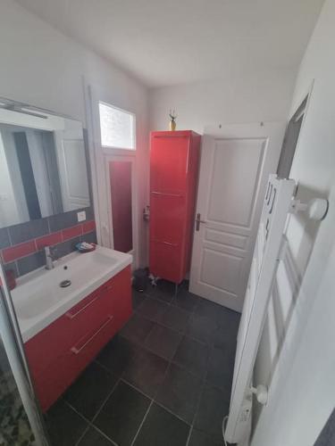 La salle de bains est pourvue d'une armoire rouge et d'un lavabo. dans l'établissement Agréable maison de ville avec piscine, à La Teste-de-Buch
