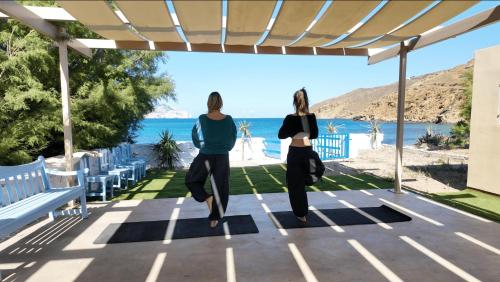 two women jumping in the air under a pergola at Lakki Village in Aegiali
