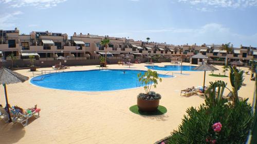 a large swimming pool in a hotel with people sitting around it at Los Geranios 21 Tenerife in Costa Del Silencio