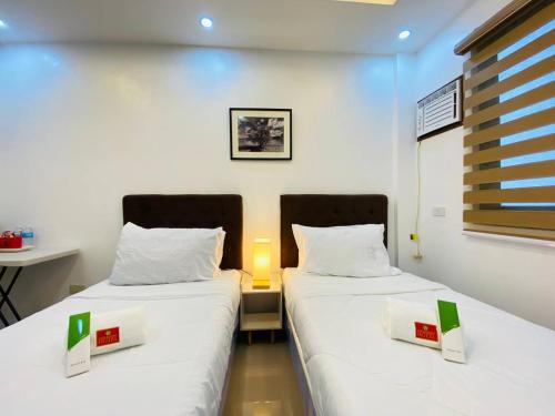 two beds in a small room with a table and a desk at Marketpoint Hotel in Mogpog