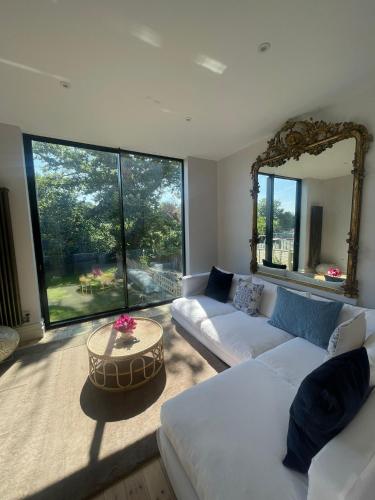 a living room with two white couches and a mirror at Beach House in Swanage