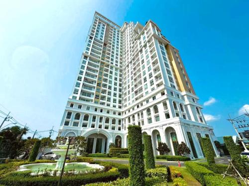 a tall white building with a garden in front of it at The Empire Chic Residence Jomtien & Yahaha in Jomtien Beach