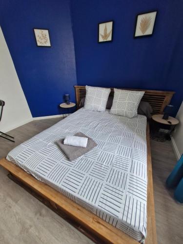 - un grand lit dans une chambre dotée d'un mur bleu dans l'établissement La famille, à Angoulême