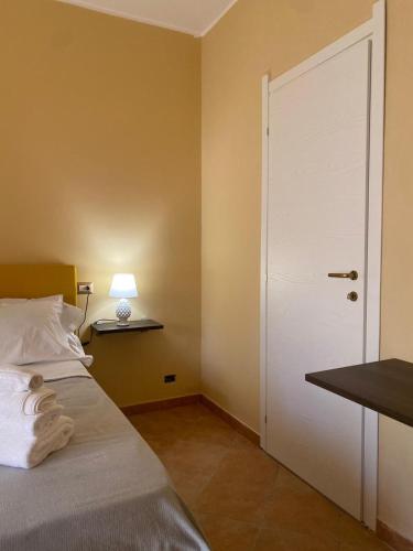 a bedroom with a bed with a white door and a lamp at Musetta sicilian hospitality in Milazzo
