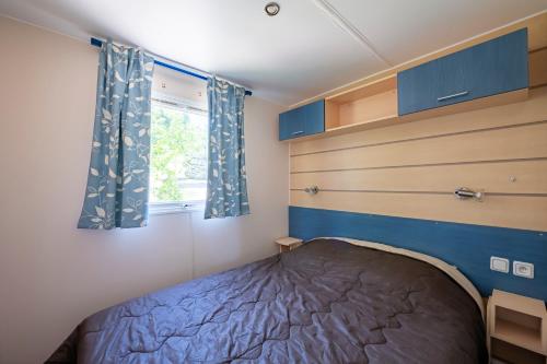 une petite chambre avec un lit et une fenêtre dans l'établissement Mobil Home classik 4-6 personnes, nature, piscine parc du pilat, à Saint-Appolinard