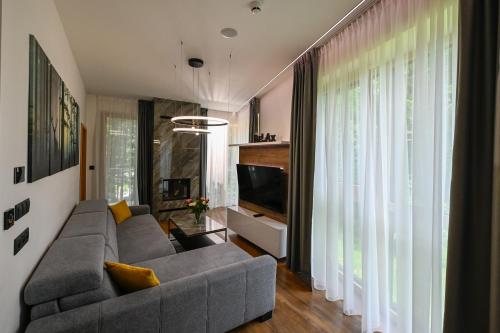 a living room with a gray couch and a television at Hotel Ovruč - rodinný apartmán 111 in Štrbské Pleso