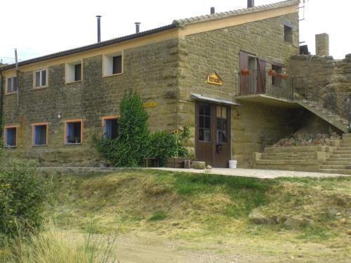 Un grand bâtiment en pierre avec un escalier se trouve devant. dans l'établissement El Pajar, à Castilsabás