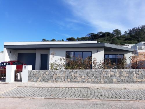 a white house with a stone retaining wall at Casa Ambiente Verde in Caldas da Rainha