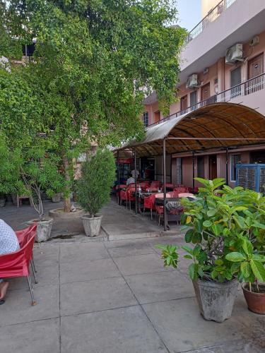 un patio esterno con tavoli, sedie e alberi di Hotel Alka a Varanasi