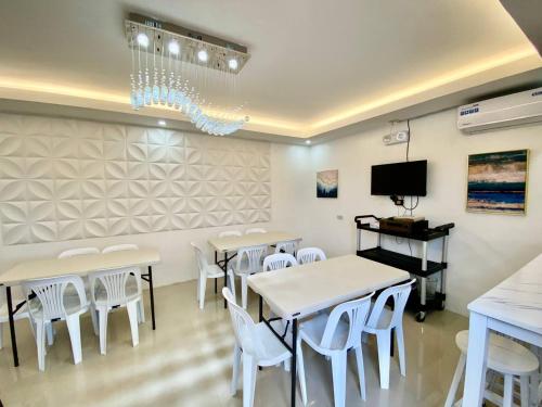 a dining room with white tables and white chairs at Marketpoint Hotel in Mogpog