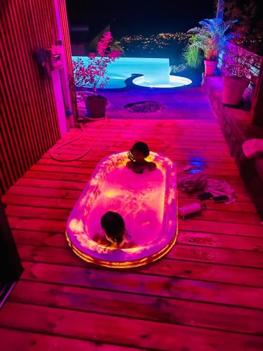 two people sitting in a hot tub with pink lights at La Villa de Jeanne in Les Cocos
