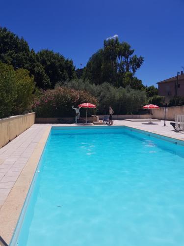 une grande piscine bleue avec deux parasols dans l'établissement Gard mobilhome, à Saint-Ambroix