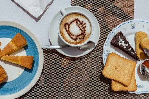 a cup of coffee next to a plate of desserts at Hotel Vecchia Oliviera in Montalcino