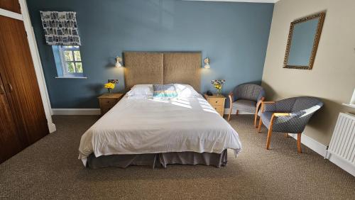 a bedroom with a large bed with blue walls at Stoke Lodge Hotel in Stoke Fleming