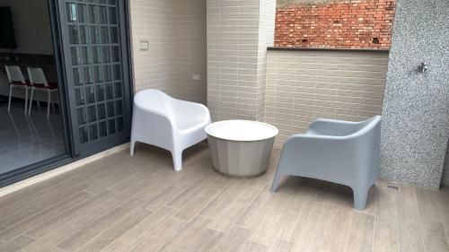 two white chairs and a trash can in a room at 粨倉文旅 in Xiluo