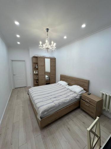a bedroom with a large bed and a chandelier at Excellent 2-room apartment near the city embankment in Astana