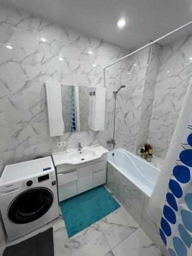 a bathroom with a sink and a washing machine at Excellent 2-room apartment near the city embankment in Astana